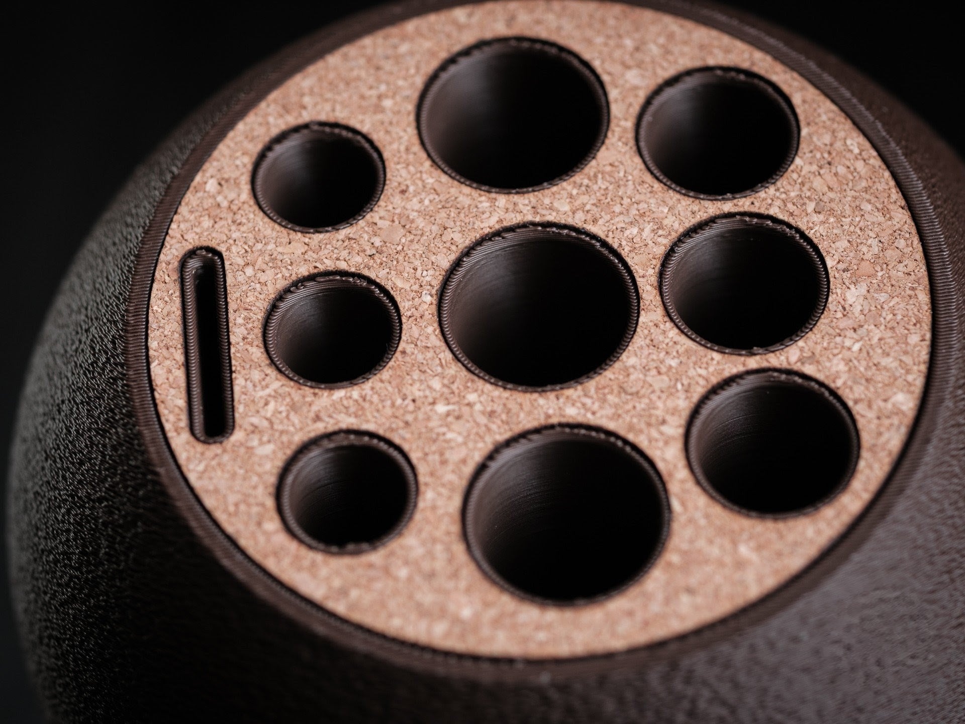 Close-up of a cylindrical object with multiple circular holes on a dark background